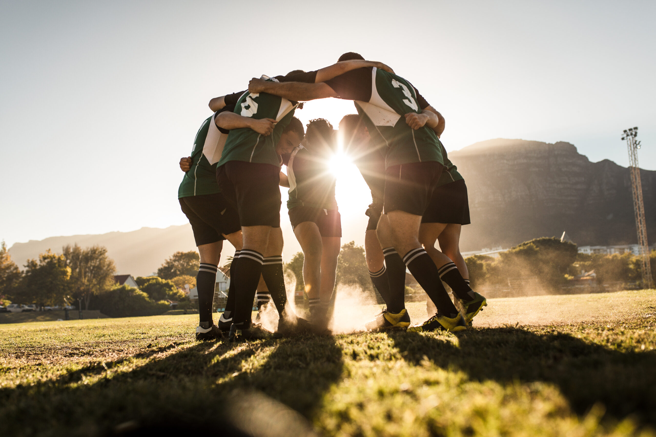 des joueurs de rugby se tenant par l'épaule en cercle