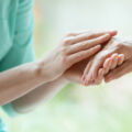 Une personne tient la main d'un malade