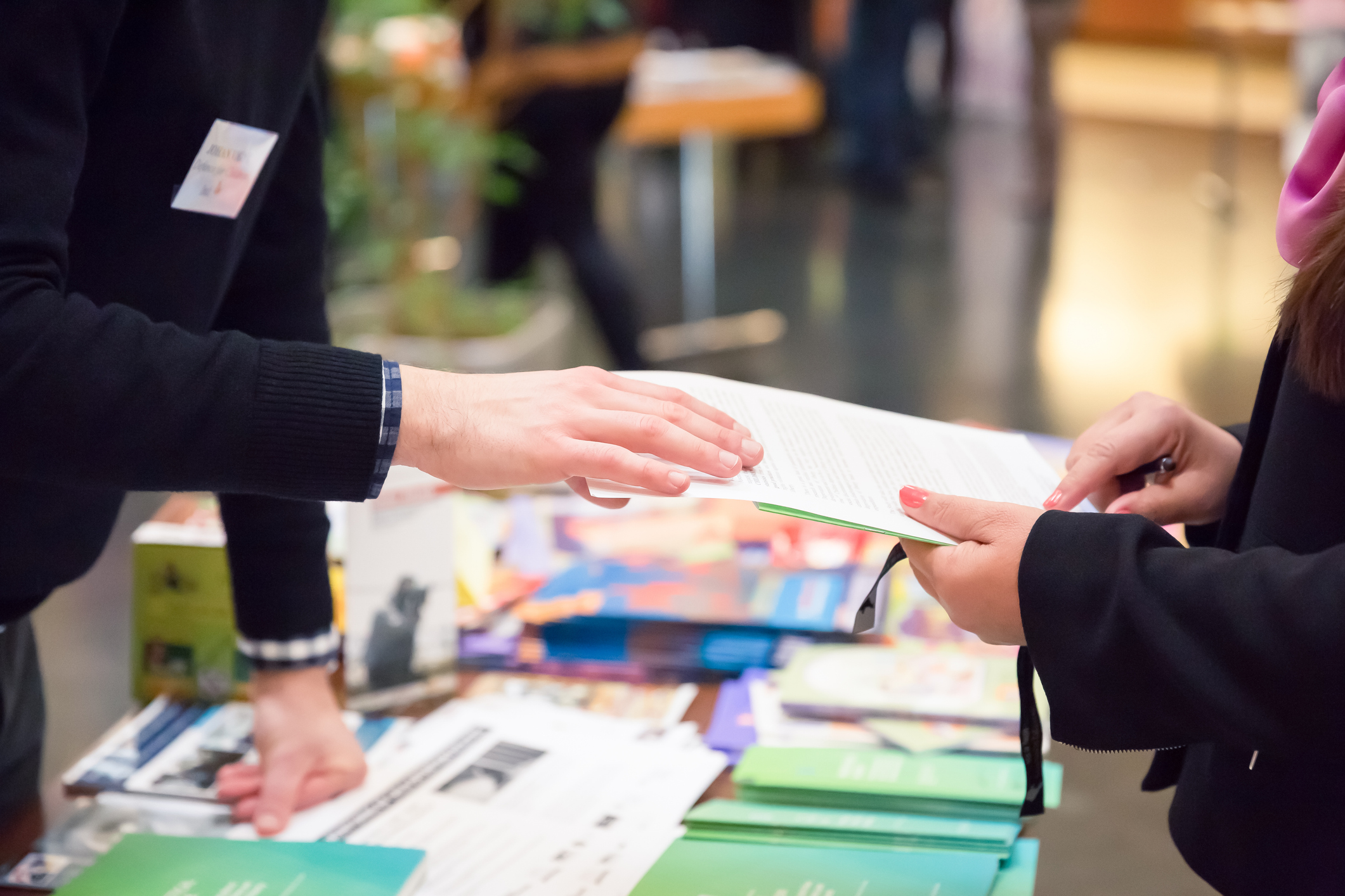 une personne tend une feuille à signer à une autre personne
