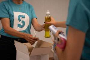Une personne tend un produit d'hygiène à une autre personne