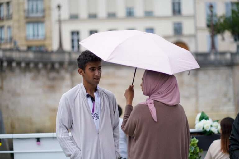 Une femme tenant un parapluie et un homme face à face en ville