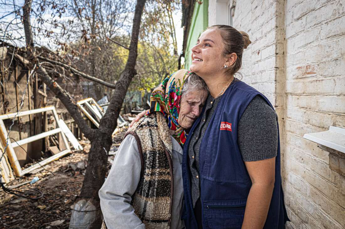 Une femme prend une autre femme dans ses bras devant une maison