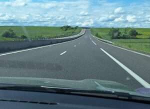 Vue depuis le pare-brise d'une voiture : la route et les champs autour