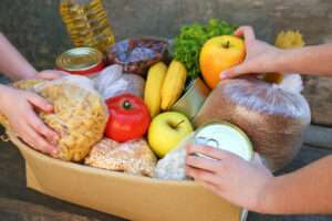 Des mains remplissent un colis alimentaire.