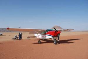 un avion rouge et blanc posé sur une base dans un milieu désertique