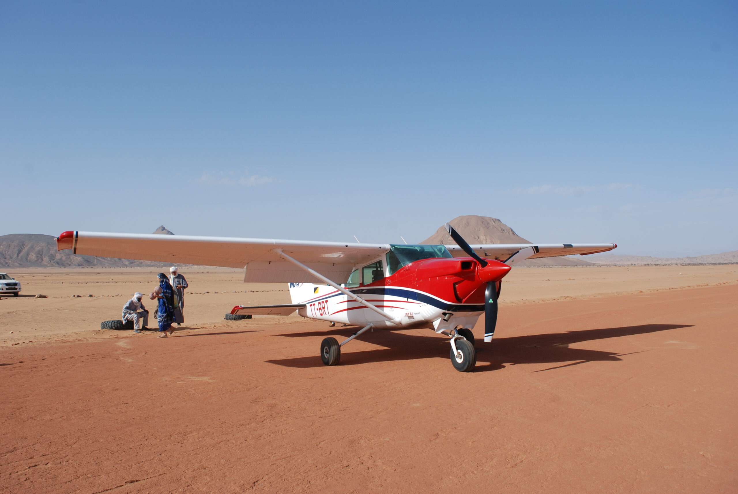 un avion rouge et blanc posé sur une base dans un milieu désertique