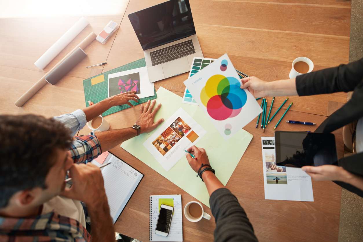 des mains autour d'un bureau regardent des projets graphiques