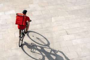 Un livreur à vélo avec un sac à dos rouge